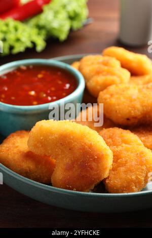 Assiette avec sauce Chili chaude et nuggets sur la table, gros plan Banque D'Images