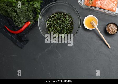 Marinade de soja dans un bol, filet de saumon et autres produits sur une table texturée gris foncé, pose à plat. Espace pour le texte Banque D'Images