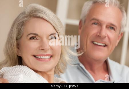 Happy senior man and woman couple assis ensemble à la maison en souriant et heureux Banque D'Images