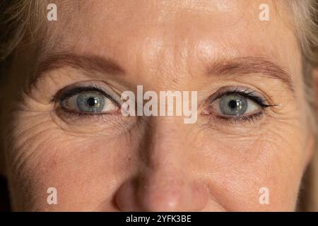 Montrant la sagesse et l'expérience, gros plan des yeux de la femme senior en mise au point, à la maison Banque D'Images