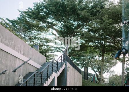 Escalier extérieur de l'hôtel menant vers le haut, entouré d'une architecture moderne et de verdure, offrant un chemin élégant vers les niveaux supérieurs dans un cadre serein. Banque D'Images