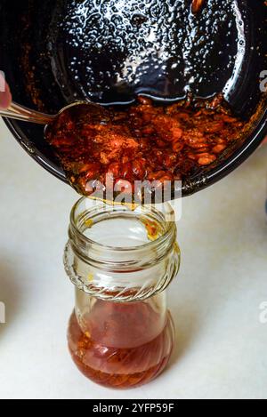 Verser la confiture cuite d'argousier d'une casserole dans un bocal en verre pour le stocker. Cuisine domestique. Banque D'Images