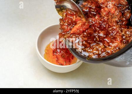 Verser la confiture d'argousier cuite d'une casserole dans un bol. Cuisine domestique. Banque D'Images