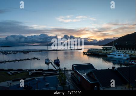 Automne lever le soleil sur la distance des montagnes enneigées et le Vagsfjorden avec un port animé et le port dans la petite ville de Harstad en Norvège, SCA Banque D'Images