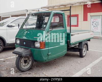 Arquato, PC, italie - 31 octobre 2024 petit APE vert piaggio trois roues Smart scooter pick-up garé devant un supermarché en italie Banque D'Images