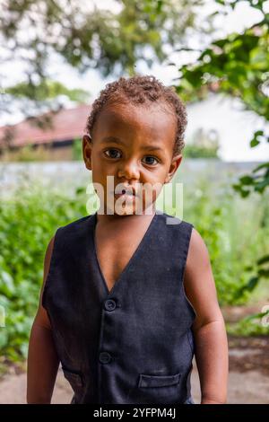 portrait d'un enfant africain aux cheveux bouclés, jouant dans la cour , jardin et maison à l'arrière Banque D'Images