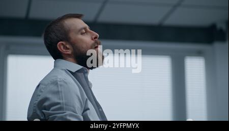 Nerveux et stressé employé de bureau respire fortement, s'assoit sur le sol après avoir détruit la salle de bureau. Homme d'affaires frustré après l'échec d'un accord commercial ou recevoir de mauvaises nouvelles. Crise financière. Épuisement du travail. Banque D'Images