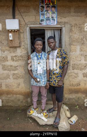 Jeunes hommes debout devant un salon de coiffure à Takpatchiomey, Couffo, Bénin Banque D'Images