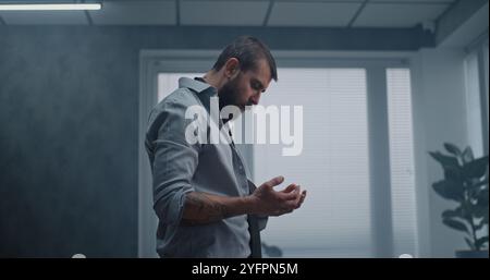 Travailleur de bureau frustré et nerveux se tient debout, respire lourdement après avoir détruit la salle de bureau. Homme d'affaires stressé après un accord d'affaires infructueux ou recevoir de mauvaises nouvelles. Perte financière. Épuisement du travail. Banque D'Images