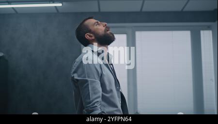 L'employé nerveux et stressé respire fortement, s'assoit sur le sol après avoir détruit la salle de bureau en raison d'un tir. Homme d'affaires frustré après l'échec d'un accord commercial ou recevoir de mauvaises nouvelles. Crise financière Banque D'Images