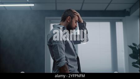 Travailleur de bureau frustré et nerveux se tient debout, respire lourdement après avoir détruit la salle de bureau. Homme d'affaires stressé après un accord d'affaires infructueux ou recevoir de mauvaises nouvelles. Perte financière. Épuisement du travail. Banque D'Images