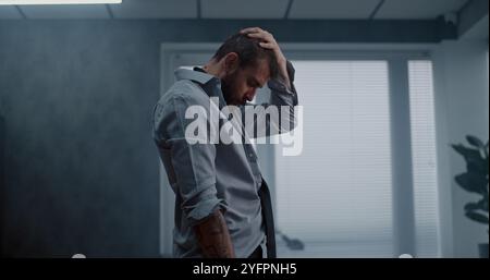 Travailleur de bureau frustré et nerveux se tient debout, respire lourdement après avoir détruit la salle de bureau. Homme d'affaires stressé après un accord d'affaires infructueux ou recevoir de mauvaises nouvelles. Perte financière. Épuisement du travail. Banque D'Images