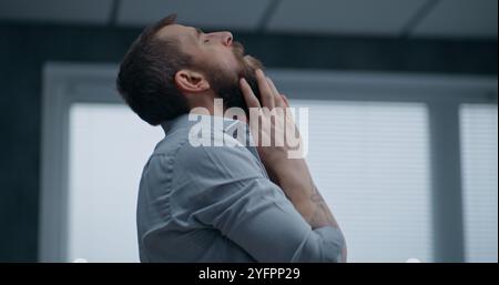 Nerveux et stressé employé de bureau respire fortement, s'assoit sur le sol après avoir détruit la salle de bureau. Homme d'affaires frustré après l'échec d'un accord commercial ou recevoir de mauvaises nouvelles. Crise financière. Épuisement du travail. Banque D'Images