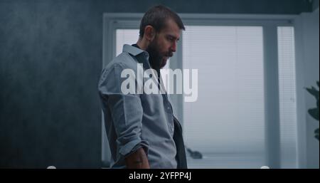 L'employé nerveux et stressé respire fortement, s'assoit sur le sol après avoir détruit la salle de bureau en raison d'un tir. Homme d'affaires frustré après l'échec d'un accord commercial ou recevoir de mauvaises nouvelles. Crise financière Banque D'Images