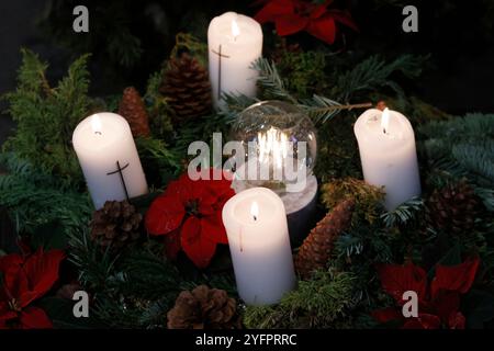 Couronne ou couronne naturelle de l'Avent dans une église catholique avec quatre bougies blanches allumées. Banque D'Images