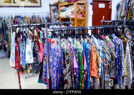 Production de batik. Le batik est un vêtement traditionnel indonésien. Chemises sur cintres dans la salle de vente. Yogyakarta. Indonésie. Banque D'Images