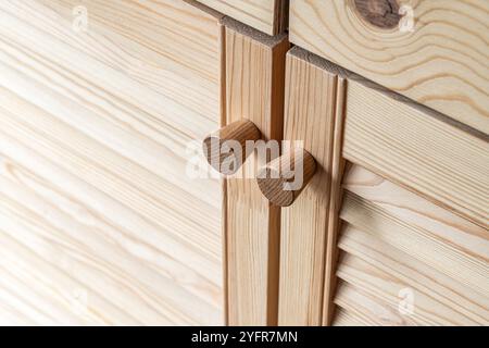 Portes à persiennes en bois avec poignées de bouton en bois gros plan. Les portes à persiennes de la cuisine extérieure sont faites de bois de pin léger avec un motif de grain naturel Banque D'Images