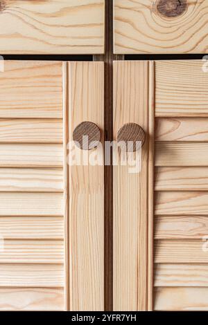 Portes à persiennes en bois avec poignées de bouton en bois gros plan. Les portes à persiennes de la cuisine extérieure sont faites de bois de pin léger avec un motif de grain naturel Banque D'Images