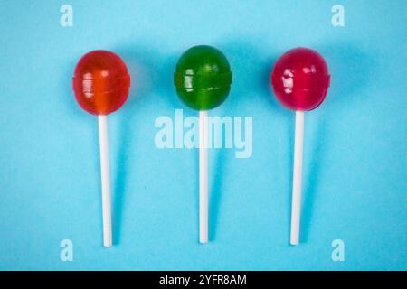 Trois sucettes sur un bâton, au fond pastel blanc, la vue d'en haut Banque D'Images