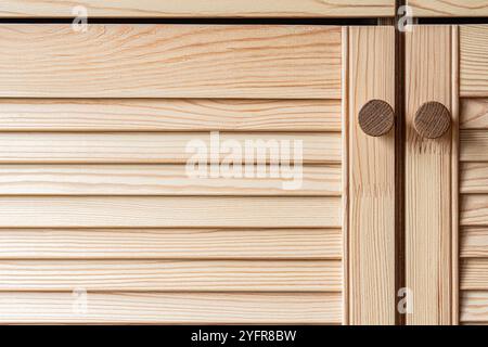 Portes à persiennes en bois avec poignées de bouton en bois gros plan. Les portes à persiennes de la cuisine extérieure sont faites de bois de pin léger avec un motif de grain naturel Banque D'Images