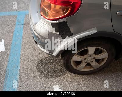 Cremona, Lombardie, Italie 27 octobre 2024 pare-chocs endommagé d'une voiture grise temporairement réparée avec du ruban adhésif, garée dans un parking, suggérant un Banque D'Images