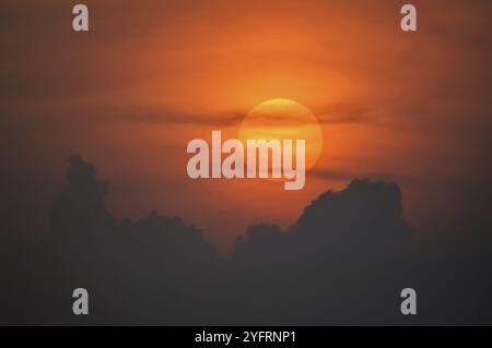 Disque solaire à travers les nuages au coucher du soleil au-dessus de l'horizon. France Banque D'Images