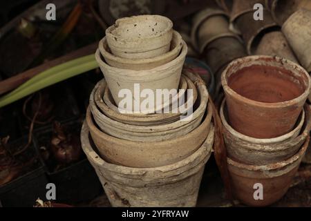 Gros plan des piles de vieux pots de fleurs en terre cuite usagés dans le hangar de jardinage Banque D'Images