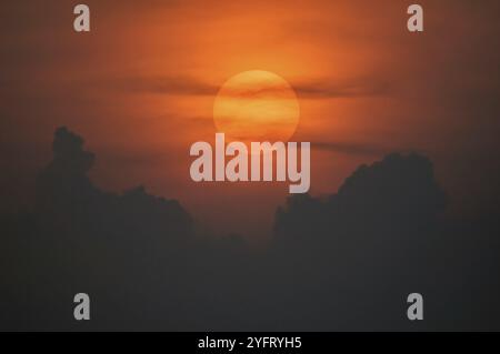 Disque solaire à travers les nuages au coucher du soleil au-dessus de l'horizon. France Banque D'Images