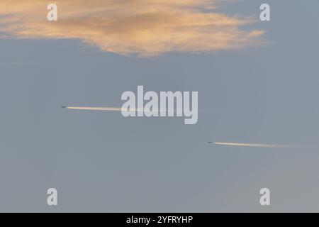 Avions de ligne en vol dans un ciel nuageux rose et orange à la fin de l'été. France Banque D'Images