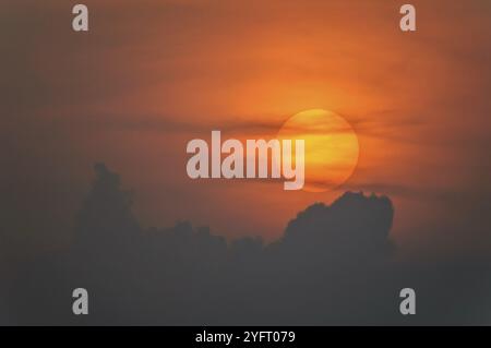 Disque solaire à travers les nuages au coucher du soleil au-dessus de l'horizon. France Banque D'Images