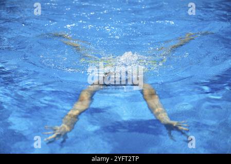 Entraînement de nageur en forme dans la piscine. Une vue aérienne d'un homme plongeant dans une piscine, formant une forme de flèche et laissant un sentier derrière lui. Profes Banque D'Images