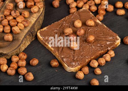 noisettes fraîches et pain avec de la pâte de noix avec du chocolat, beurre de chocolat délicieux et sucré avec des noix sur l'ardoise noire Banque D'Images