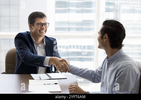 Heureux jeune homme d'affaires donnant poignée de main au consultant financier Banque D'Images