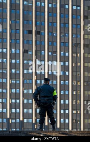 Un gardien de sécurité vêtu d'un uniforme professionnel, vu de derrière, se tient devant un immeuble de bureaux moderne. Sécurité, surveillance. Rome, Italie Banque D'Images