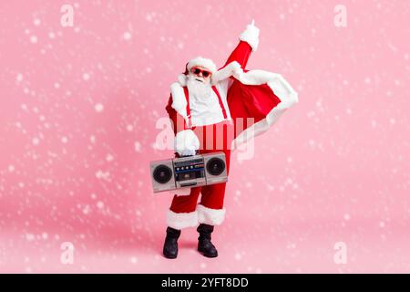 Concept de fête disco de Noël de Noël. Pleine longueur photo cool funky surpoids santa claus prêt écouter boom box rétro rythme son porter chapeau de lunettes de soleil Banque D'Images