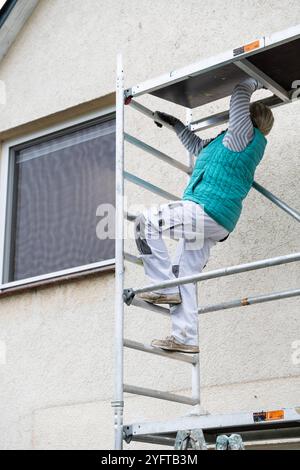 Gerüstbauerin, Malerin baut ein mobiles Gerüst am Einfamilienhaus auf, modèle libéré für redaktionelle Nutzung, Gerüstbauer *** échafaudage, peintre érige un échafaudage mobile sur une maison individuelle, modèle libéré pour usage éditorial, échafaudage 20241105-DSC 8704 Banque D'Images