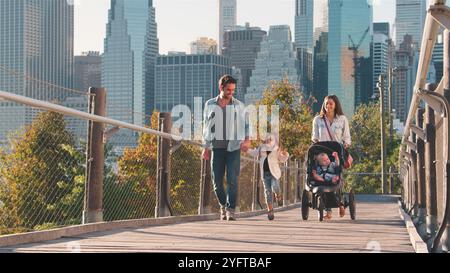 Journée en famille à New York avec maman poussant bébé en buggy avec Manhattan Skyline en arrière-plan Banque D'Images