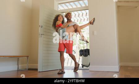 L'homme transporte la femme au-dessus du seuil de lune de miel ou de location de vacances Banque D'Images