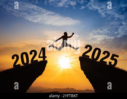 Un jeune homme saute entre 2024 et 2025 ans au-dessus du soleil et à travers sur l'écart de silhouette de colline Banque D'Images