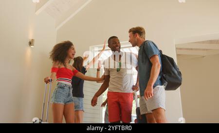 Groupe excité d'amis avec bagages arrivant à la location de vacances d'été Banque D'Images