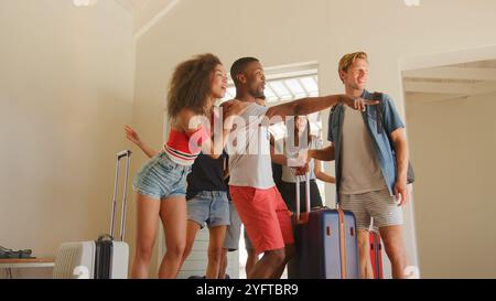 Groupe excité d'amis avec bagages arrivant à la location de vacances d'été Banque D'Images