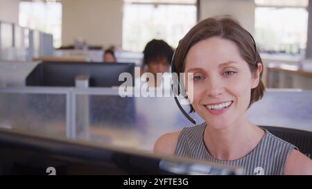 Portrait d'une femme du service d'assistance à la clientèle ou d'un agent de télévente au bureau portant des casques Banque D'Images