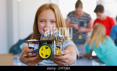 Portrait de femme souriante étudiant tenant le véhicule robot dans la classe de codage informatique de l'école Banque D'Images