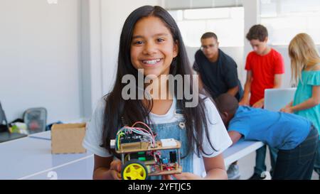 Portrait de femme souriante étudiant tenant le véhicule robot dans la classe de codage informatique de l'école Banque D'Images