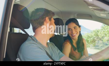 Couple adulte moyen assis et conduisant une voiture de location pendant les vacances d'été Banque D'Images