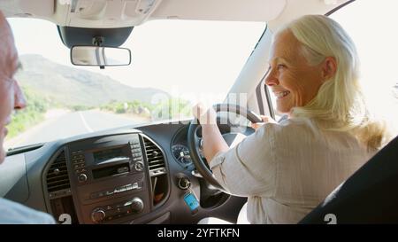 Couple senior assis et conduisant voiture de location pendant les vacances d'été Banque D'Images