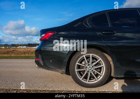 Gros plan de BMW 320 noire avec roues en alliage sur route pavée Banque D'Images