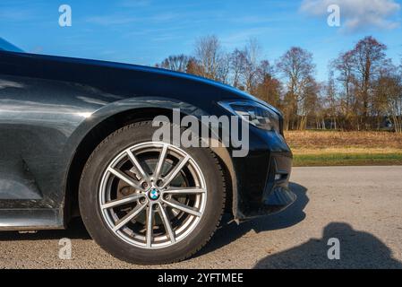 Gros plan de la section avant de la BMW 320 sur une route pavée en milieu rural Banque D'Images