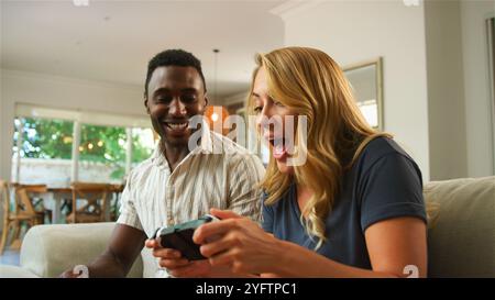 Deux amis jouent avec enthousiasme à des jeux vidéo sur un canapé. Banque D'Images