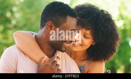 Un couple joyeux partage un moment d'amour en plein air sous le soleil. Banque D'Images